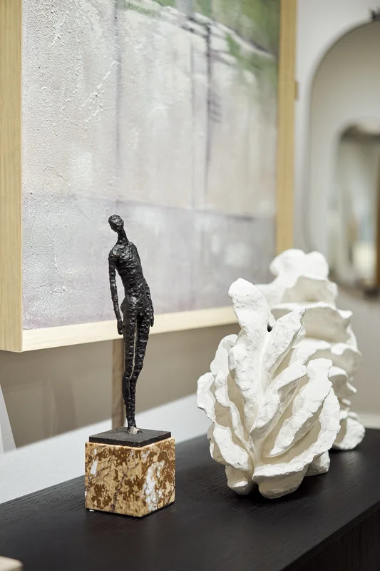 Detalle decorativo sobre mueble negro con escultura de metal y piezas cerámicas con relieve
