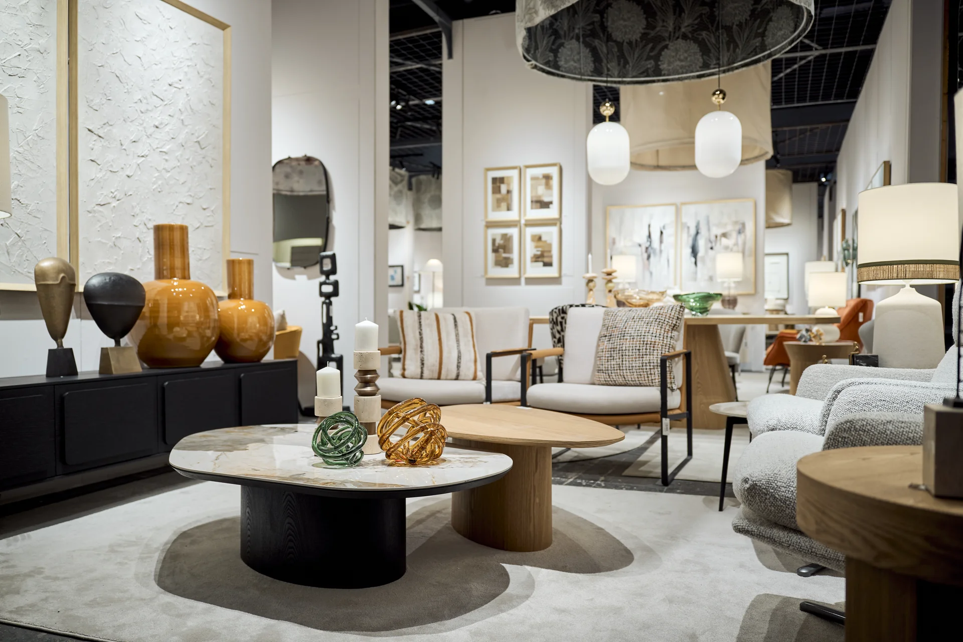 Stand de VP Interiorismo en Feria Hábitat Valencia con mesas de centro de madera, sofás y jarrones de cristal ámbar