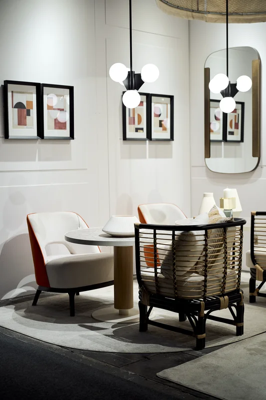 Zona de exposición en Feria Hábitat Valencia con sillón de ratán, butaca tapizada y lámpara de suspensión moderna