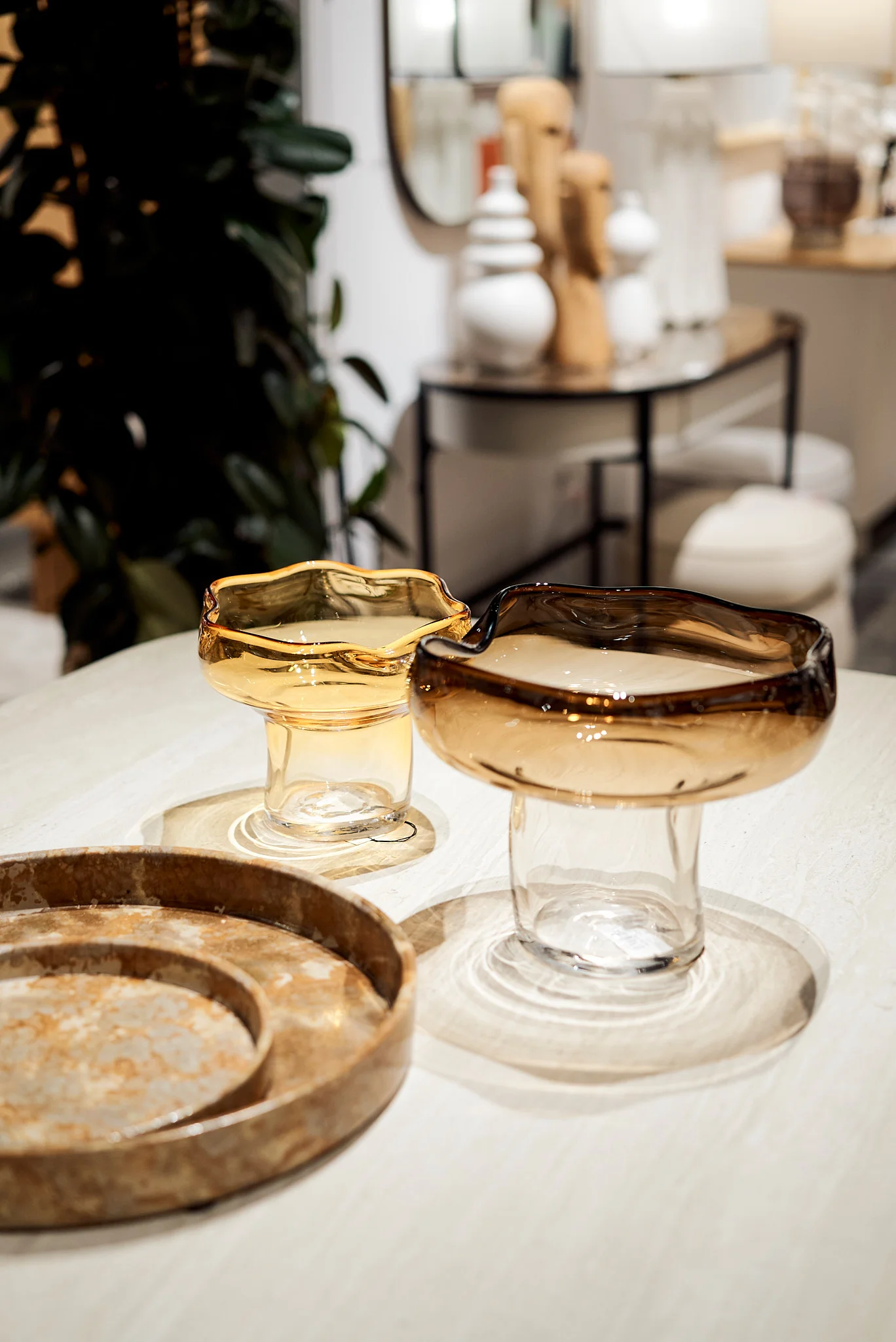 Centros de mesa de cristal soplado en tonos ámbar y marrón sobre bandeja texturizada.